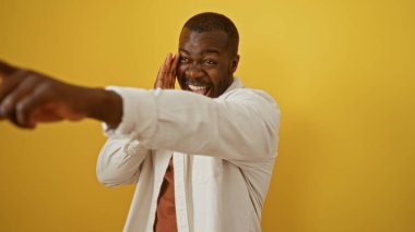 Genç, çekici, Afrikalı, Amerikalı, kollarını uzatarak izole edilmiş sarı arka planda gülen bir adam.