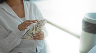 Parlak ofis ortamında manikürlü elleri olan, iş kıyafetleri içinde kısmen görülebilen bir kadın bize mali ya da kapalı alanda yapılan parayla ilgili bir iş öneriyor.