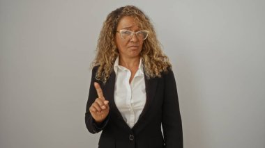 Gözlüklü orta yaşlı bir kadın parmağıyla hareket etmiyor, beyaz bir arkaplanda tek başına duruyor..