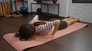 Kapalı bir spor salonunda paspas üzerinde egzersiz yapan, spor salonuna odaklanan ve modern bir spor merkezinde esneme hareketleri yapan bir kadın..