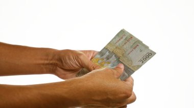 El ele tutuşan Endonezya rupia banknotları izole edilmiş beyaz bir zemin üzerinde finansal işlemlerin özünü yakalıyor.