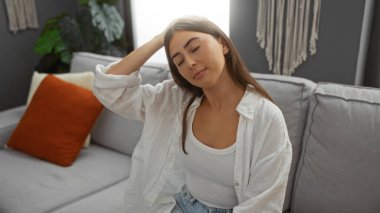 Modern bir oturma odasında rahat bir koltukta uzanan bir kadın, doğal ışıklandırması olan şık bir evde rahatlık ve rahatlık sergiliyor..