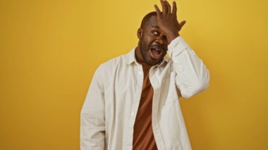 Yakışıklı, Afro-Amerikalı bir adam, izole edilmiş sarı arka plana şaşırmış görünüyor.