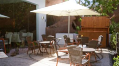 Lanzarote 'deki açık kafe. Arka planı bulanık. İçinde boş hasır sandalyeler ve şemsiye altında masalar var.