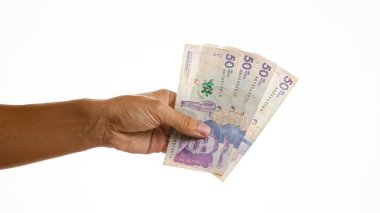 İzole edilmiş beyaz arka plan üzerinde el ele tutuşan Kolombiya pesoları, ayrıntılı para birimi notları sergileniyor.