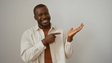 Gülümseyen adam, açık avuçlarını beyaz bir arka plana doğru gösteriyor. Güven ve yakınlık yayıyor..