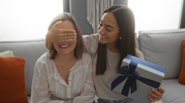 Kızı sürpriz bir anneyle oturma odasında, aile sevgisini ve mutluluğunu kapalı mekanda gösteriyor.