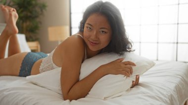 Güzel genç bir kadın yatak odasında bir yatakta dinleniyor, evde huzurlu bir anın tadını çıkarıyor.