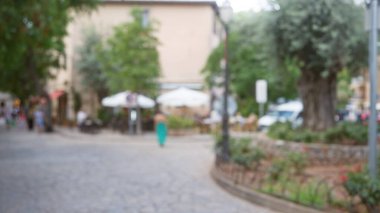 Odaklanamadığı Mallorca caddesinde yürüyen bulanık bir kadın. İspanya 'da açık kafeler ve yeşillikler var..