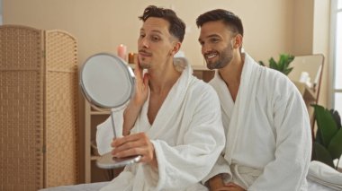 Kaplıcadaki erkekler aynaya bakıyorlar. Huzurlu Sağlık Merkezi 'nde beyaz elbiseler giyiyorlar.