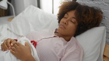 Kıvırcık saçlı genç kadın rahat yatak odasında huzur içinde uyuyor. İçerideki huzur ve huzuru somutlaştırıyor. Doğal güzelliği ve huzurlu ev ortamını ön plana çıkarıyor..