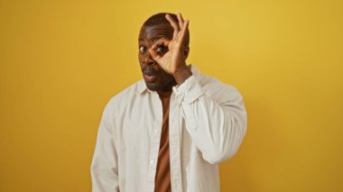 Beyaz gömlekli yakışıklı genç adam izole edilmiş sarı arka planda iyi bir jest yapıyor.