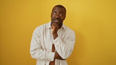 Yakışıklı, Afro-Amerikan genç adam izole edilmiş sarı arka plan üzerinde kafa yoruyor.