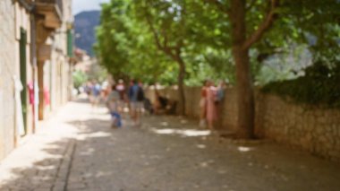 Bulanık insanlar Mallorca 'da açık bir yolda yürüyor, İspanya' da sokakları kaplayan ağaçlar ve arka planda binalar var.