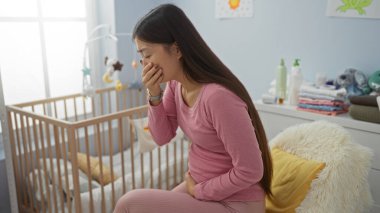 Sıcak bir yatak odasındaki bir yatakta oturan kadının midesi bulanıyor. Yanında hafif aydınlatılmış bir ev içinde beşiği var. Rahatsızlık veren bir anı resmediyor..