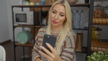 Rahat oturma odasında akıllı telefon kullanan bir kadın, modern dekorla çevrili, sıcaklığı ve konforu zarif stil ve yumuşak ışıklandırmayla yayıyor, huzurlu ev ortamını aktarıyor..