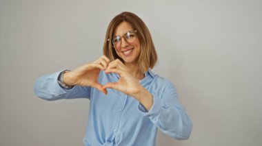 Güzel sarışın kadın gülümsüyor ve elleri ile izole beyaz bir arka plan üzerinde kalp şekli oluşturuyor.