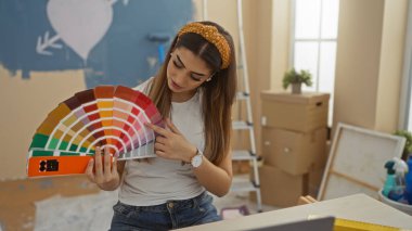 Woman choosing colors in new home living room surrounded by boxes, showcasing interior design choices in modern apartment setting. clipart