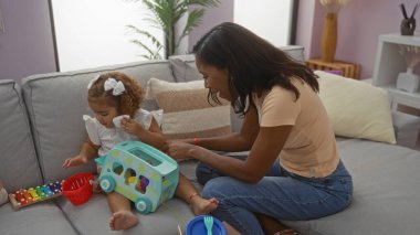 Anne ve kızı, sıcak, aile dostu bir ortamla çevrili, sıcak bir oturma odasında oyuncaklarla oynuyor..