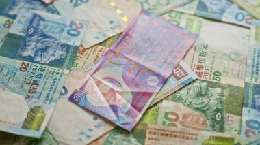 Düz bir zemine saçılmış renkli Hong Kong Doları banknotları canlı para birimi detayları ve tasarım unsurları sergiliyor..