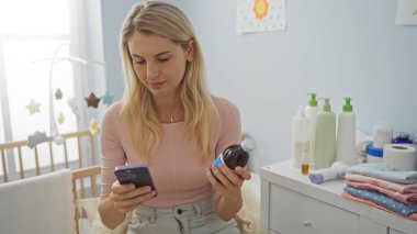 Bebek bakımı malzemeleriyle çevrili, rahat yatak odasında ilaç şişesini tutan bir kadın, ev ortamını besliyordu..