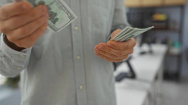 Ofis ortamında dolar sayan bir adam profesyonel bir ortamda paranın nasıl kullanıldığını gösteriyor..