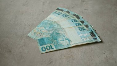 Brezilya banknotları 100 reais değerinde beton bir yüzeye saçılmış..