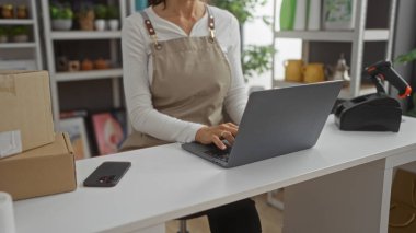 Ev dekorasyonunda dizüstü bilgisayar kullanan bir kadın. Etrafı kutularla ve dekorasyonlarla çevrili.