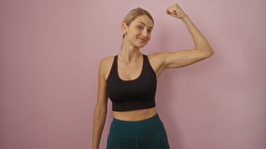 Pembe arka plana karşı kaslarını kasan, güçlü, formda ve güçlü bir kadın..