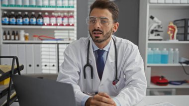 Steteskoplu yakışıklı doktor modern klinikte meslektaşlarıyla tıbbi detayları tartışıyor..