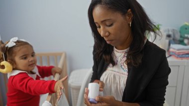 Elinde çocuk beşiği olan bir şişeyle yatak odasına uzanan bir kadın ev ortamında aile sevgisini sergiliyor..