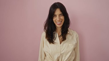 Çekici genç İspanyol kadın pembe bir arka planda gülümsüyor.