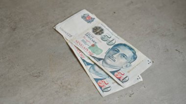 Singapur banknotları somut bir yüzeye yerleştirilmiş 50 dolarlık banknotları gösteriyor..