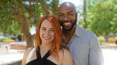 Mutlu ırklar arası bir çift, güneşli bir günün tadını çıkarıyor. Şehir parkında, sevgilerini ve güçlü ilişkilerini sergiliyorlar..