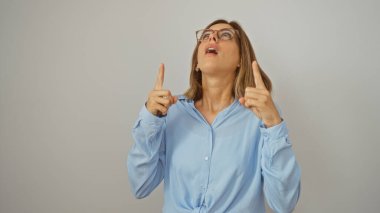 Beyaz arka planda mahsur kalmış mavi gömlekli ve gözlüklü şaşırmış bir kadın.