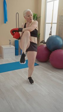 Spor salonunda kickboks antrenmanı yapan bir kadın spor salonunda spor malzemelerinin altını çizerek aktif bir yaşam tarzı sergiliyor..