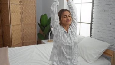 Rahat yatak odasında uzanan kadın rahat bir sabah rutinini parlak pencerenin yanındaki rahat yatakta gösteriyor..