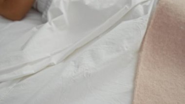 Bir kadın yatakta dinleniyor, esmer, aydınlık bir yatak odasında huzur içinde uyuyor, dinlenmek ve rahatlamak için sakin ve rahat bir ortam sergiliyor..