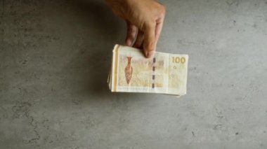 Elele tutuşan Danimarka 100 kronu beton bir yüzey üzerinde, İskandinav paralarını basit bir arka plan ayarında sergiliyor..