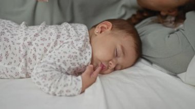 Yatak odasında bebeğiyle birlikte uyuyan bir kadın. Evde hassas bir aile anını yakalıyor. Sakin bir sabah rutiniyle sevgi ve bağlarını gösteriyor..