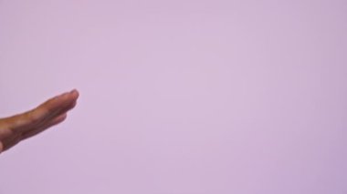 Adamın eli açık pembe bir zemine karşı dalga gibi hareket ediyor. Rahat ve dinamik bir jesti vurguluyor..