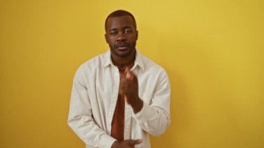 Afro-Amerikalı bir adam tişört giyiyor ve düşünceli bir poz veriyor. Yüzü ve eli çenesinde, kuşkularını dile getiriyor ve izole edilmiş sarı arka plan üzerinde sorguluyor.