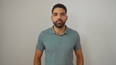 Genç İspanyol adam afallamış ve parmağıyla işaret ederek, izole beyaz arka plan üzerinde şaşkınlık içinde bakıyor