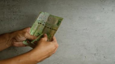 Elinde Hong Kong Doları banknotları tutan adam somut bir zemine karşı, çeşitli değerlerde yerel para gösteriyor..