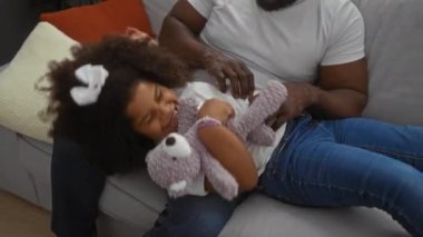 Baba, rahat oturma odasındaki kanepede kızı eğlendirirken aile sevgisini ve neşesini kapalı mekanda ifade ediyor..