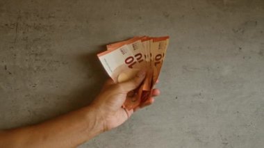 10 avroluk banknotları kaba beton bir arka planda tutan adam, güç ve kararlılığını gösteriyor.