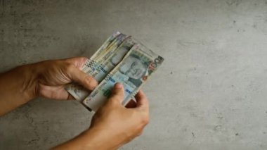 Gri beton arka planda Peru sol banknotlarının el ele tutuşması ve sayımı