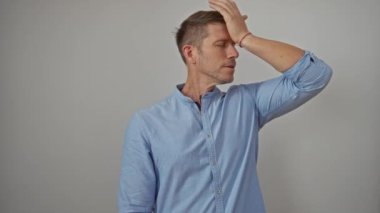 Mavi tişörtlü adam düşünceli görünüyor. Alnı düz duvara dayalı. Düşüncelerini ve içyüzünü ifade ediyor..