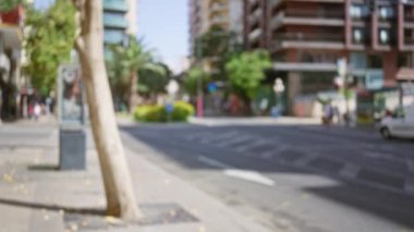Bulanık kentsel sokak sahnesi, binalar, ağaçlar ve belirsiz insanlar güneşli bir şehirde açık havada çekildi..