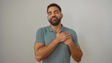 Sağlık bilinci, elleri göğsünde duran genç İspanyol adam, gülümsüyor, izole beyaz arka planda minnet dolu bir jest yapıyor.